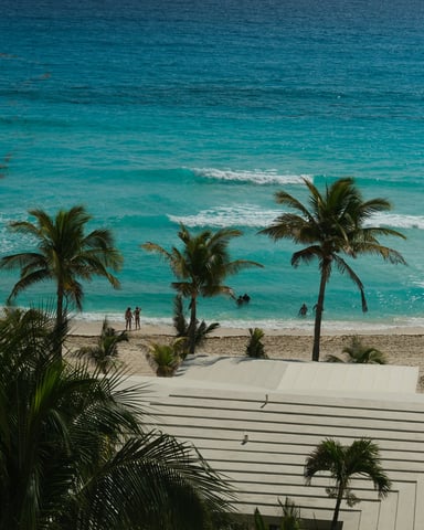Overhead view of turquoise Caribbean waves breaking on white sand beach with palm trees